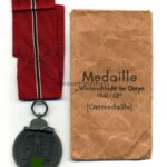 Ostmedaille mit Verleihungstüte, Hst. 65 – „Klein & Quenzer A.G, Idar Oberstein“, Winterschlacht im Osten 1941/42