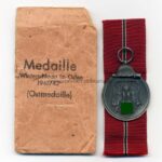 Ostmedaille mit Verleihungstüte, Hst. 127- "Moritz Hausch A.G., Pforzheim", Winterschlacht im Osten 1941/42
