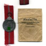 Ostmedaille mit Verleihungstüte, Hst. 23 – “Arbeitsgemeinschaft für Heeresbedarf in der Graveur & Ziselierinnung, Berlin”, Winterschlacht im Osten 1941/42  -Selten!-